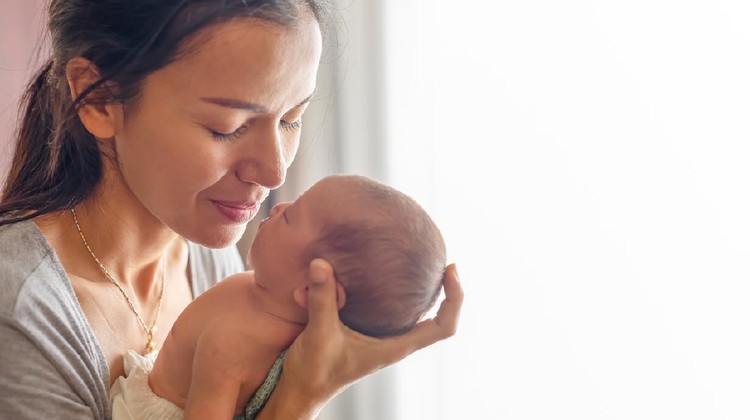 1040213716 Beautiful mother kissing here little cute baby on her palm. Mother take care her little girl at home. One week newborn girl.