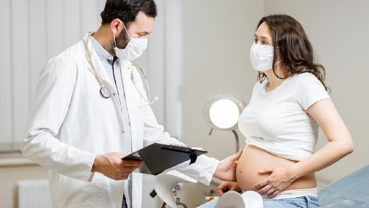 Doctor with a pregnant woman in medical masks during an examinations. Concept of new rules for the use of masks in medicine after or during a pandemic