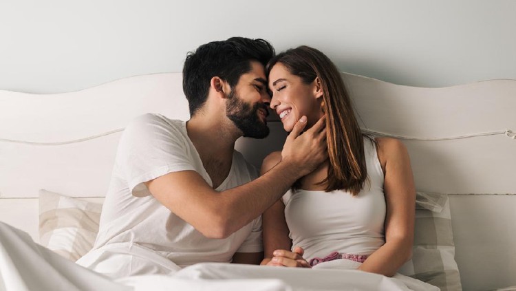 Affectionate young couple relaxing in bed and having a romantic moment