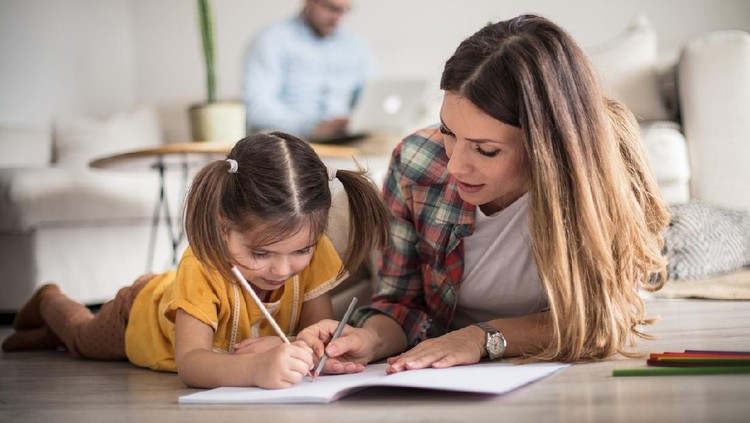 Getting help with my tasks. Little girl working her homework with mother. Focus is on foreground.