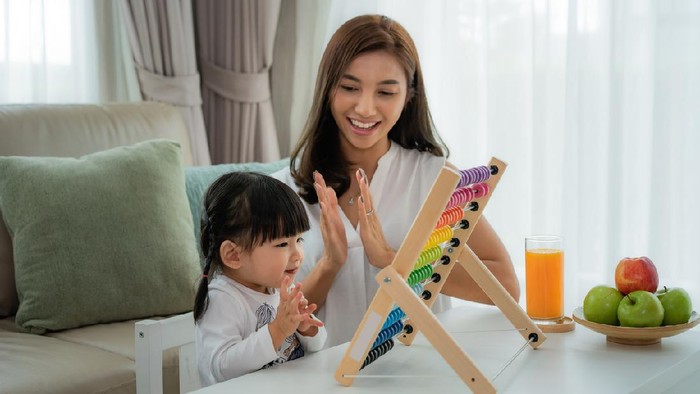 Happy Asian young mother and daughter playing with abacus, early education at home.