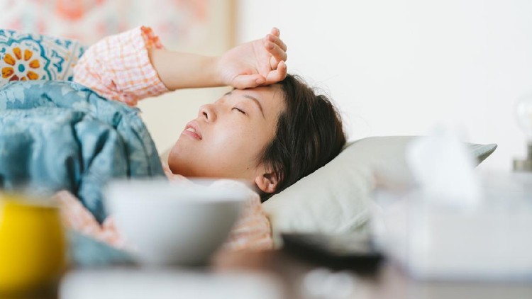 A women is feeling sick and sleeping on a sofa at home.