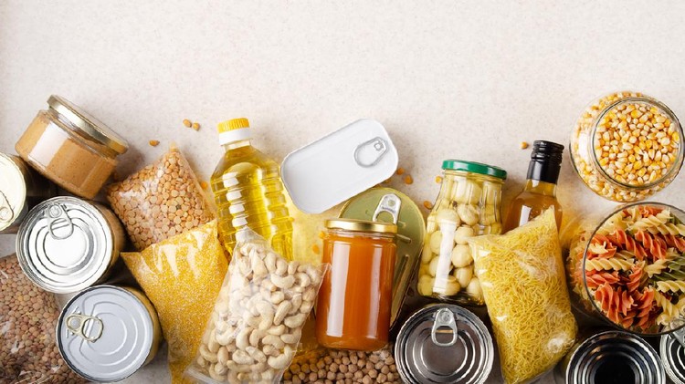 Flat lay view at kitchen table full with non-perishable foods. Spase for text