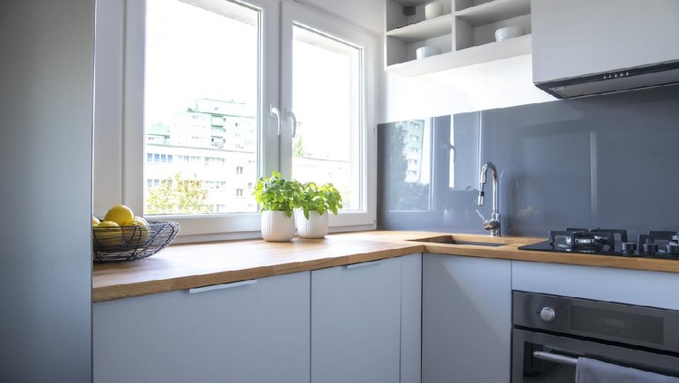 Herbs and lemons on wooden counter of small kitchen with white cupboards