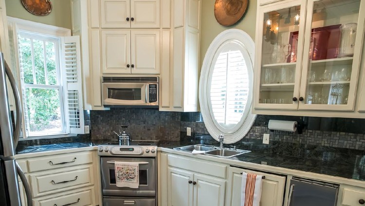 small kitchen in a pool guest house with appliances and cabinets and a counter and custom lighting