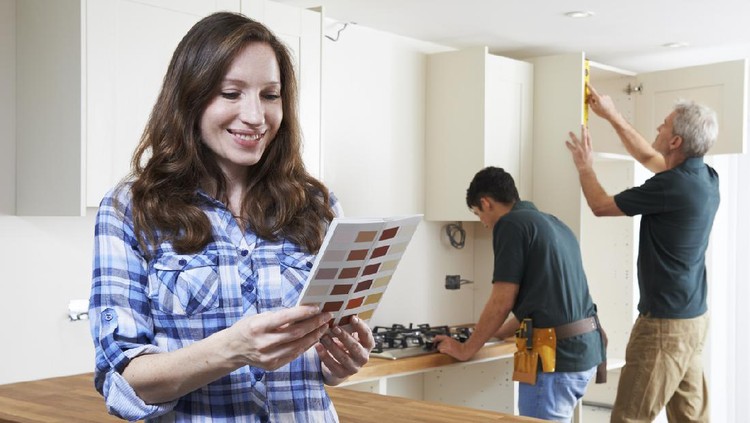 Woman Looking At Paint Chart In New Kitchen