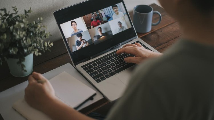 View over businesslady shoulder seated at workplace desk look at computer screen where collage of many diverse people involved at video conference negotiations activity, modern app tech usage concept