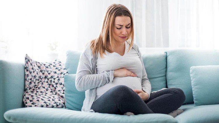 Young pregnant woman suffering from abdominal pain at home