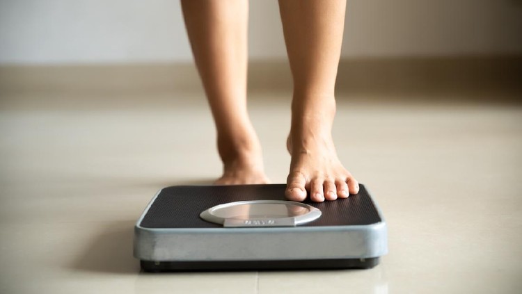 Female leg stepping on weigh scales. Healthy lifestyle, food and sport concept.