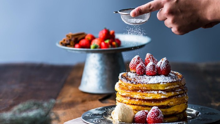 Strawberry pancakes with maple syrup.Sprinkle with powdered sugar on top.