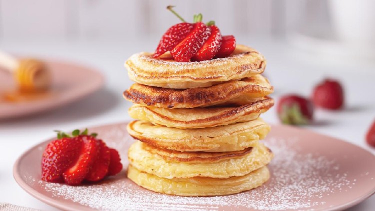 Freshly baked pancakes with strawberries on a natural wood background