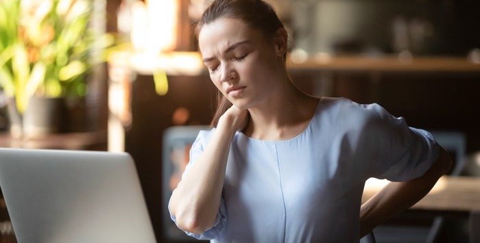Stressed upset business woman feeling backpain working on laptop sitting in incorrect posture, tired fatigued student rub back suffer from spine muscular pain injury lumbar backache concept in office