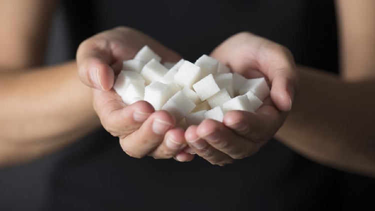 Caucasian female is holding sugar cubes in hand.
