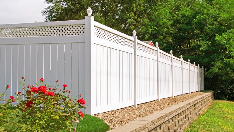 Beautiful white vinyl fence in back yard with nice landscaping in the foreground and background