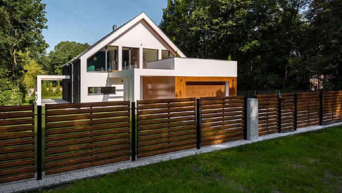Spacious white house with wooden decoration on garage and wood style fence