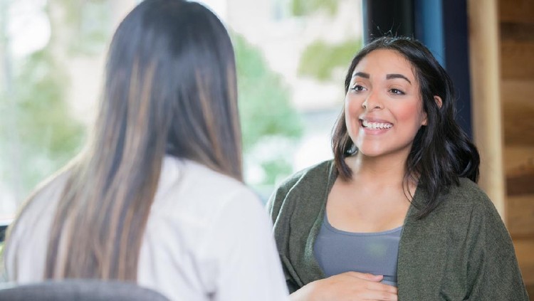 Young adult Hispanic expectant mother is discussing her pregnancy with a midwife during a support group meeting or childbirth class.