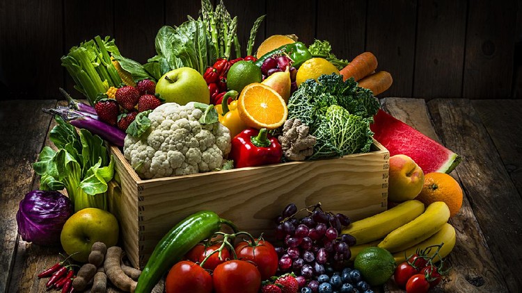 Healthy food: large selection of fresh organic multicolored vegetables in a crate shot on dark wooden table. Fruits and vegetables included in the composition are watermelon, oranges,lime, lemons, banana,grape, strawberries, apples, pears, blueberries, tamarind, kale, tomatoes, squash, asparagus, celery, eggplant, carrots, lettuce, edible mushrooms, bell peppers, cauliflower, ginger, corn, bok choy, raw potatoes, chili peppers among others. High resolution studio digital capture taken with Sony A7rII and Sony FE 90mm f2.8 macro G OSS lens