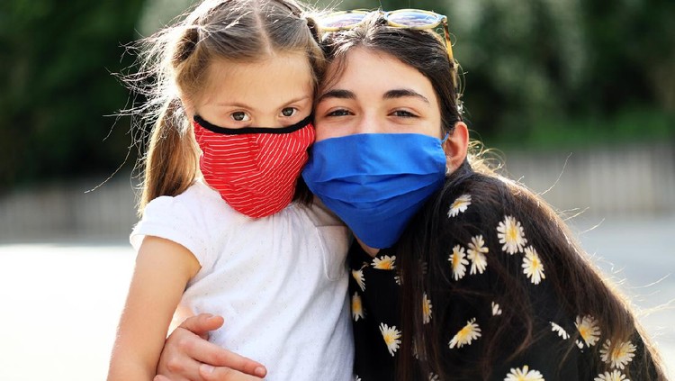 1227608796 Two cheerful girls wearing face protective mask having fun outdoors
