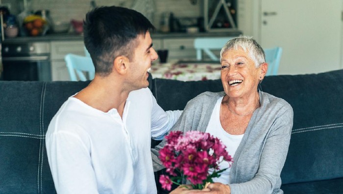 Young man gives flowers to his mother with love