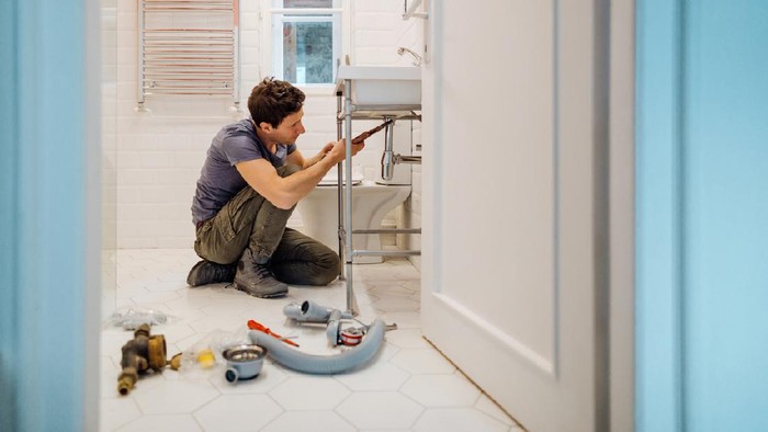 Young man fixing a leak under the bathroom sink