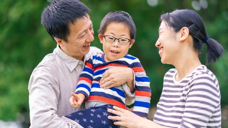A small boy with down syndrome is getting love from his caring parents.
