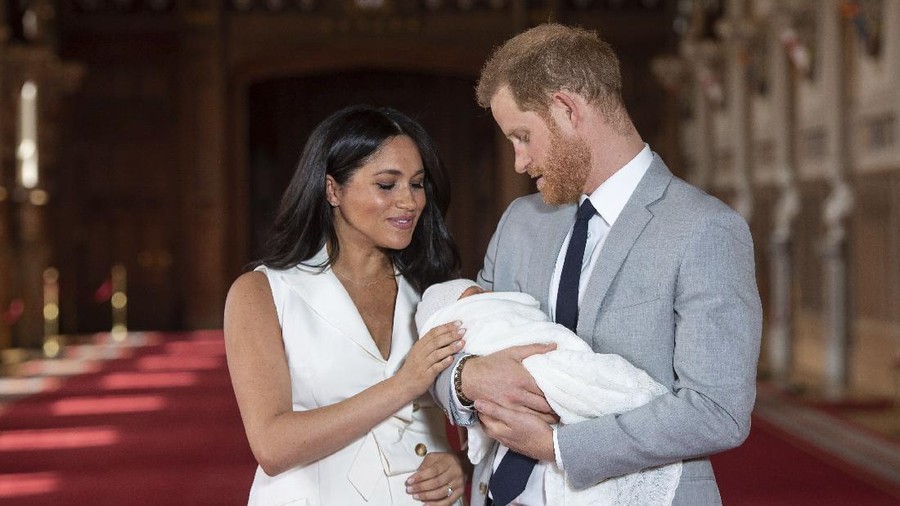 FILE - In this Wednesday May 8, 2019 file photo, Britain's Prince Harry and Meghan, Duchess of Sussex, pose during a photocall with their newborn son Archie, in St George's Hall at Windsor Castle, Windsor, south England. One of the most dramatic claims in Prince Harry and Meghan's interview with Oprah Winfrey was that their son was denied a royal title, possibly because of the color of his skin. Queen Elizabeth II has nine great-grandchildren, including Archie. They are not princes and princesses, apart from the three children of Prince William, who is second in line to the throne and destined to be king one day. (Dominic Lipinski/Pool via AP, File)
