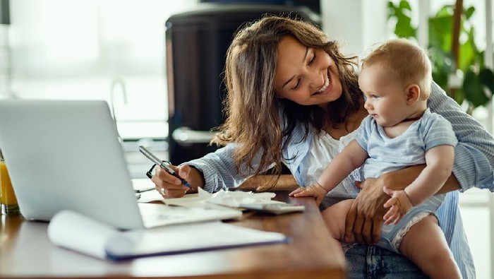 Young happy mother going through home finances and communicating with her baby son.