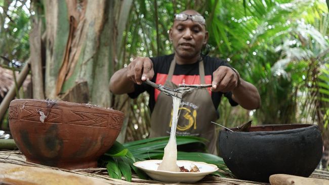 Semangkuk papeda yang kenyal dan lezat disajikan dengan kuah kuning ikan yang kaya rempah khas Papua