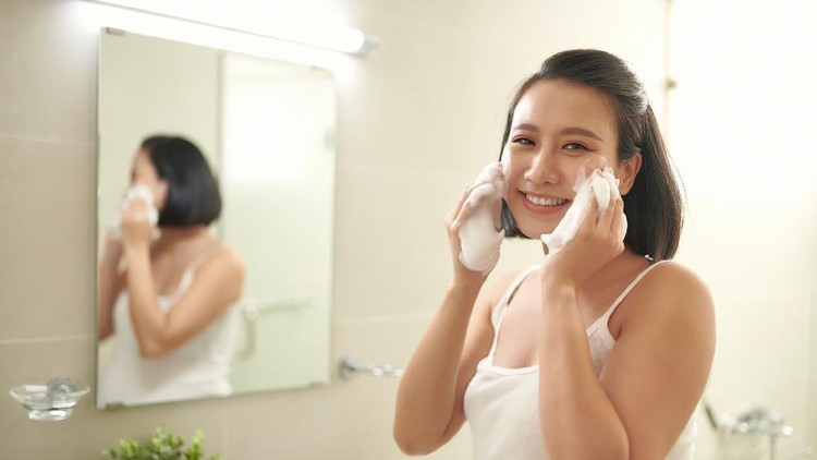 Pregnant woman splashing face with water above bathroom sink
