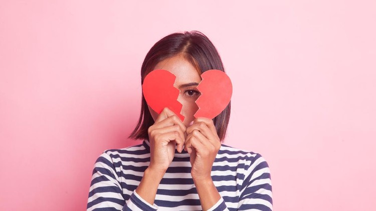 Beautiful young Asian woman with broken heart on pink background