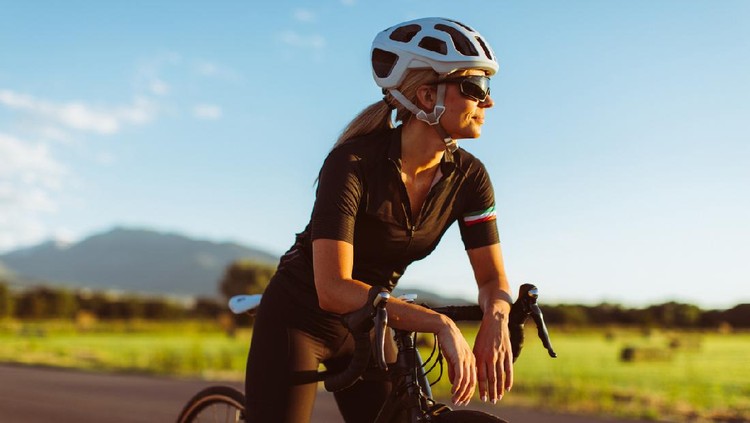 A female and woman rides her road bike along rural roads in Utah, USA, during a warm and sunny summer day. She loves to bicycle and to be outdoors living a healthy lifestyle.