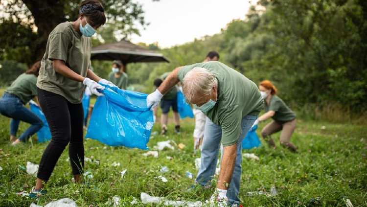 Volunteers picking up garbage while cleaning public park, they are wearing protective face masks for protection against virus during covid-19 pandemic