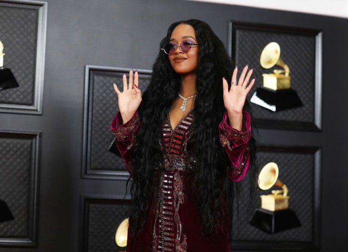 H.E.R hadir memakai jubah berwarna velvet dari Dundas World yang dipadukan dengan long sleeves dan celana, serta sepasang kacamata warna ungu senada/Sumber/LA Times.