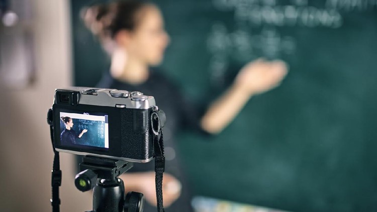 Young teacher teaching remotely using camera to stream lesson.