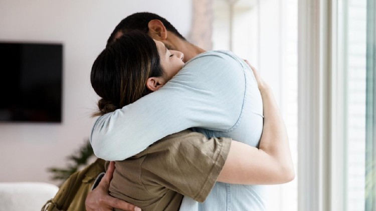 Sad mid adult  female soldier hugs her husband goodbye as she leaves for military duty.