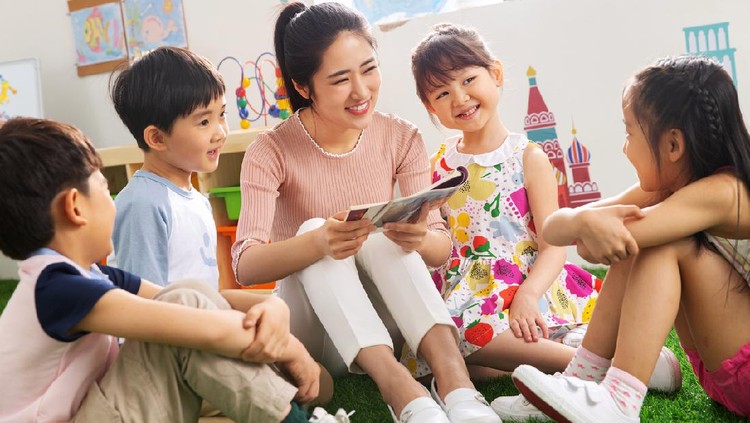 dongeng Young Asian mother sitting on the floor in the bedroom reading book to little daughter, enjoying family bonding time together at home