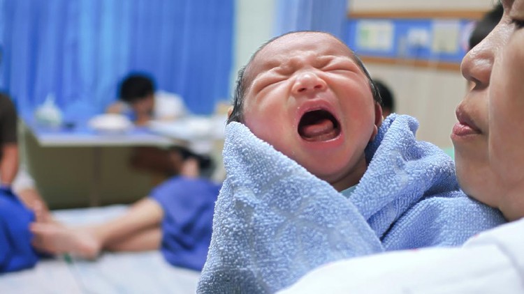 Mother holding newborn tiny baby crying.
