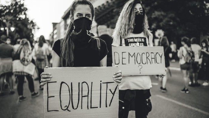 Two young women protesters holding placards with text 