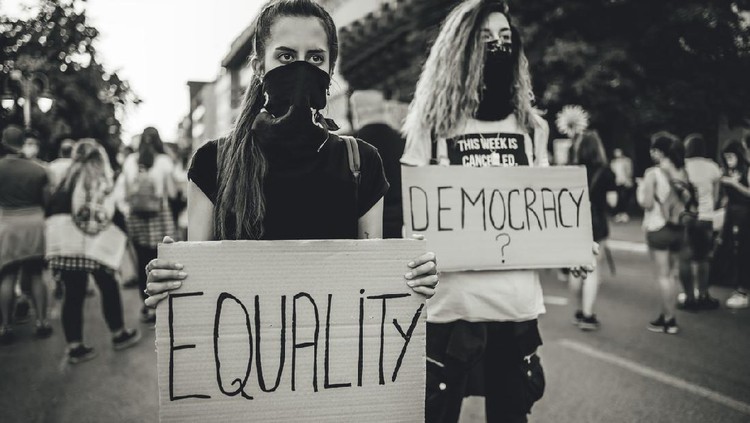 Two young women protesters holding placards with text 