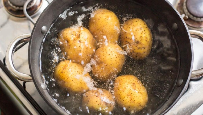 Potatoes boiling in a saucepan on a gas hob.