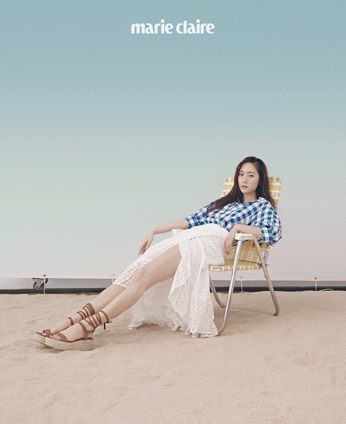 Tampil lebih santai, Krystal menggunakan perpaduan check shirt dan wrap skirt serta wedges cokelat. Look ini semakin memancarkan vibes liburan ya, Ladies! (Foto: marieclairekorea.com)