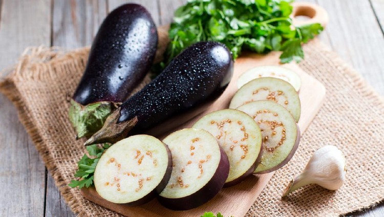 Eggplant slices on cutting board on wooden background