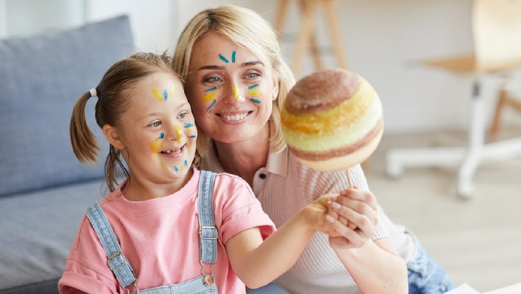 1263995694 Smiling mother showing her daughter with down syndrome the model of the planet