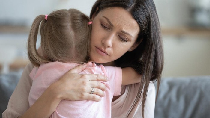 Worried young foster care parent mother comforting solacing embrace adopted little child daughter give care and protection at home, loving concerned adult mom hug sad small girl consoling kid concept