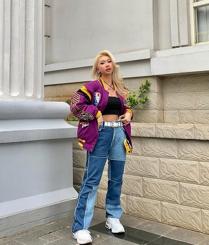 Tampil dengan crop top, varsity jacket, dan color block jeans bikin penampilan Dillah semakin stand out. Ia juga mengenakan belt dan sneakers putih untuk membuat looknya tampak balance. (foto: instagram.com/dillaprb)