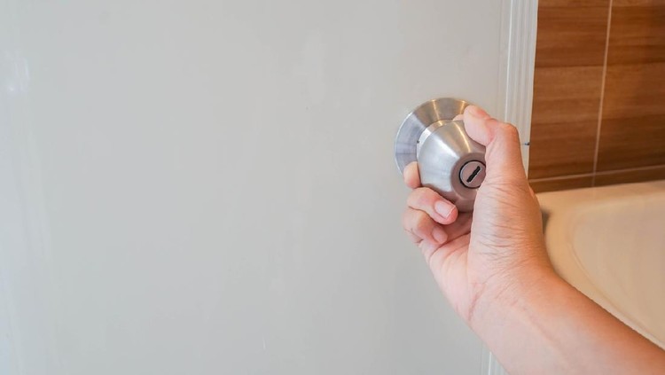 close up women twists doorknob to enter the bathroom