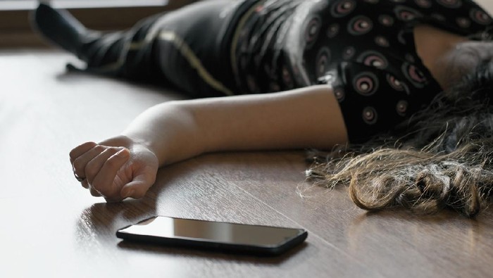 Woman lying on the floor at home, phone fallen near her hand. Crime scene, epilepsy, unconsciousness, faint, stroke, accident or other health problem.