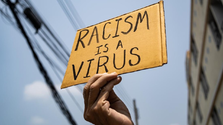A man holding Racism is a Virus sign