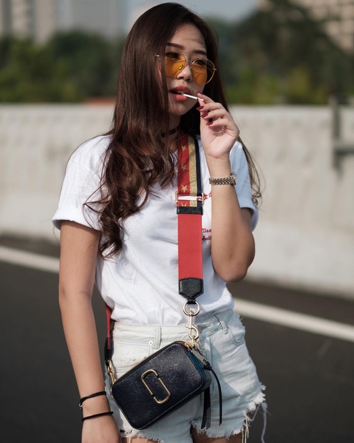 Memadukan t-shirt putih lengan pendek putih dengan denim hot pants warna senada bisa jadi inspirasi buat tampil stylish. Kamu juga bisa pilih sling bag warna hitam dengan strape merah untuk memaksimalkan penampilan (Foto: www.instagram.com/siscakohl/).