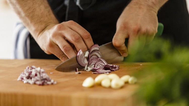 Slicing red onion on cutting board, close-up